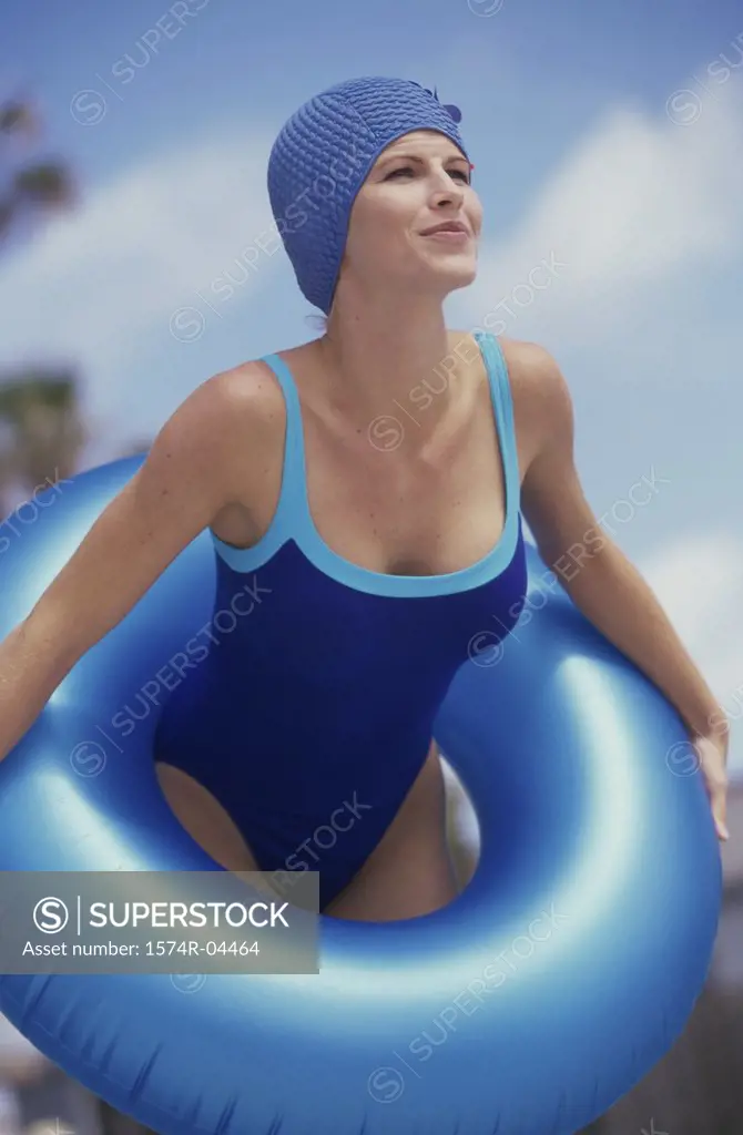 Young woman standing on the beach holding an inflatable ring