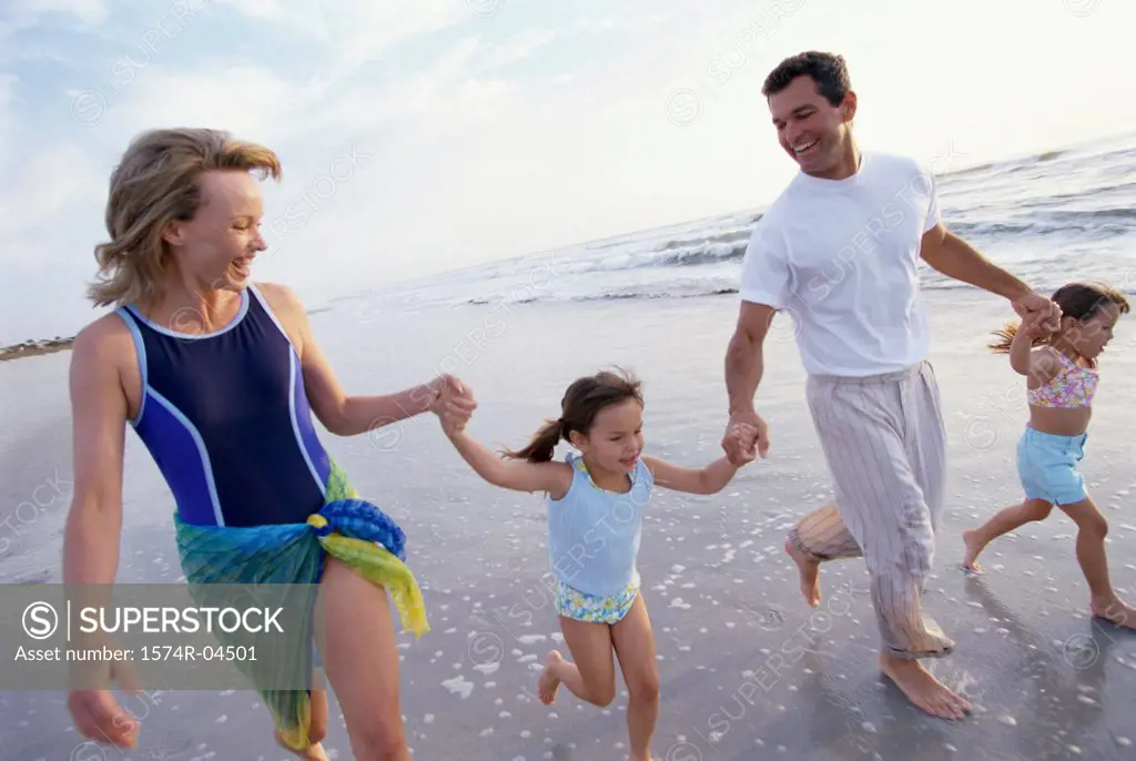 Mid adult couple walking with their two daughters on the beach