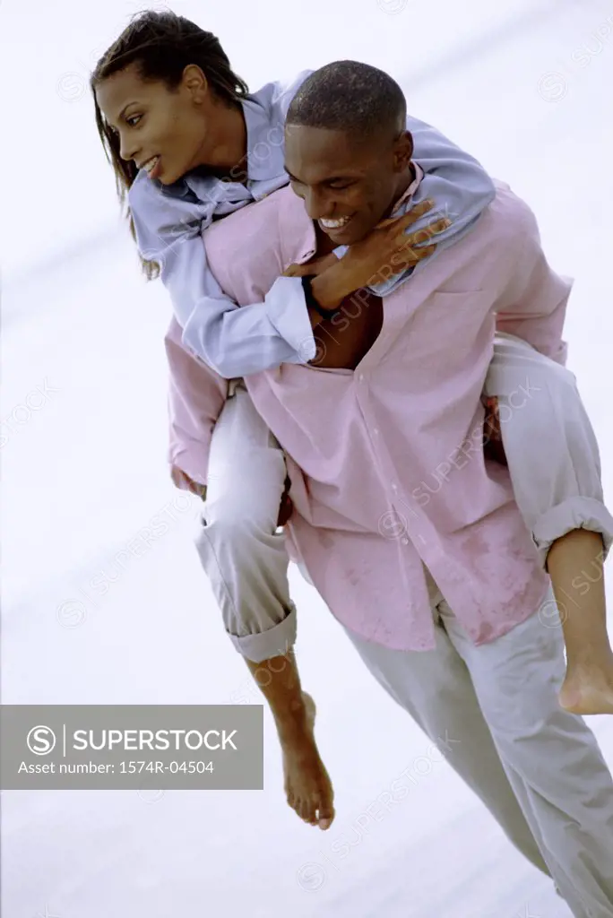 Young woman riding piggyback on a young man on the beach
