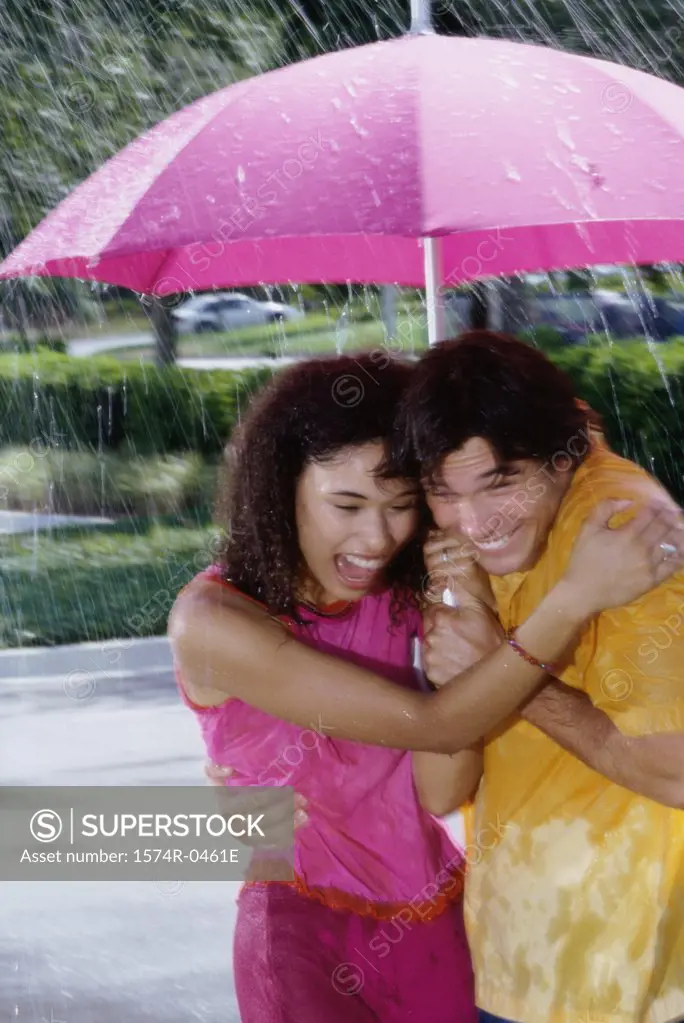 Young couple standing under an umbrella