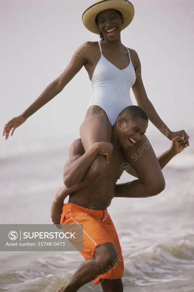 Young man carrying a young woman on his shoulders at the beach