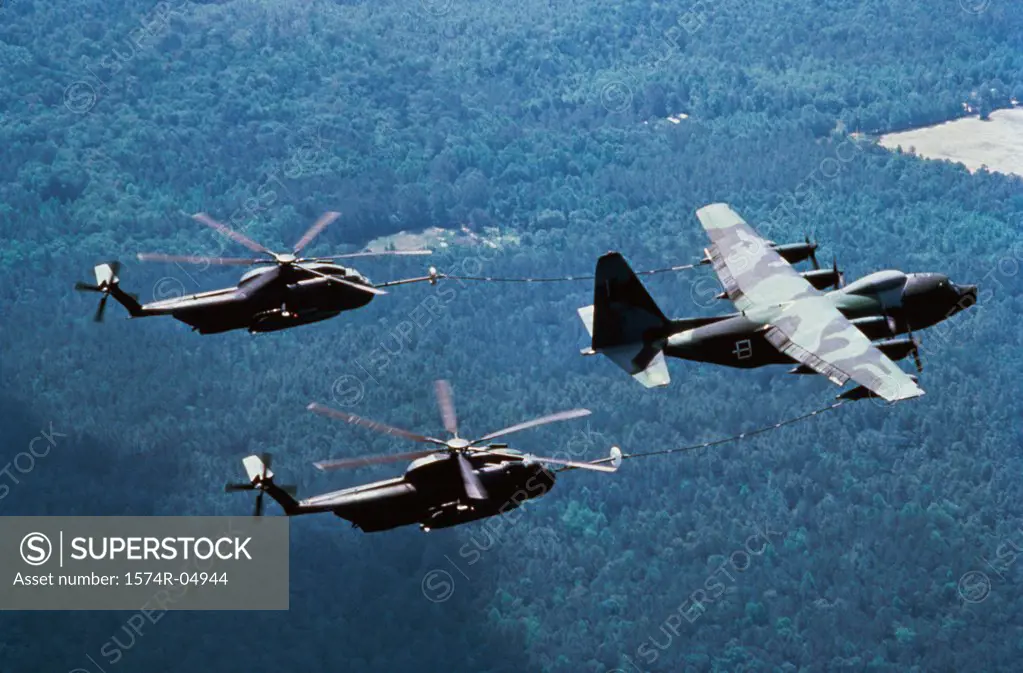 Aerial view of a KC-130 aircraft refueling two CH-53 helicopters