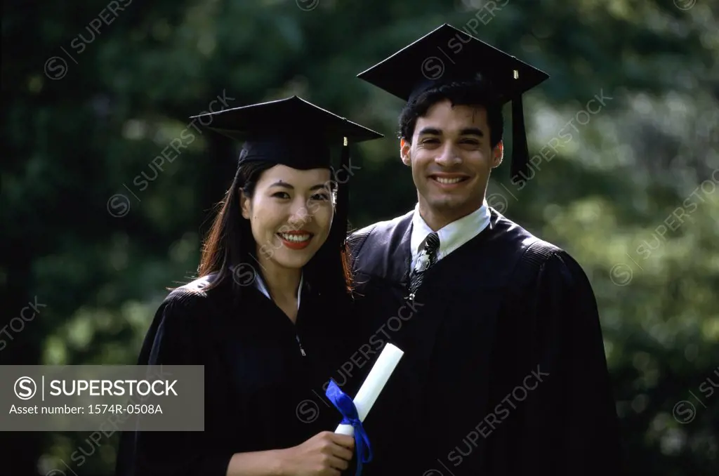 Portrait of a young woman and a young man wearing graduation outfits
