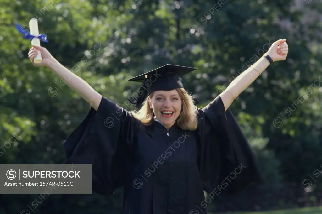 Portrait of a young woman wearing a graduation outfit holding a diploma