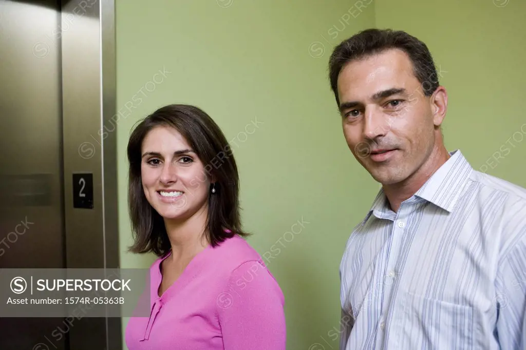 Portrait of a businesswoman and a businessman standing near an elevator