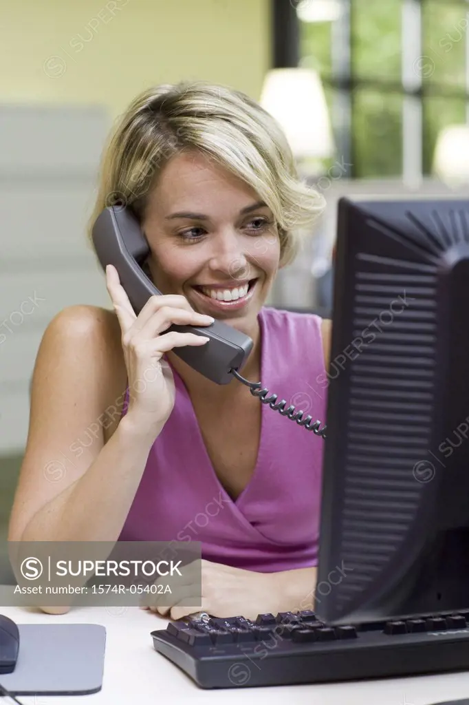 Businesswoman sitting in front of a computer talking on a telephone