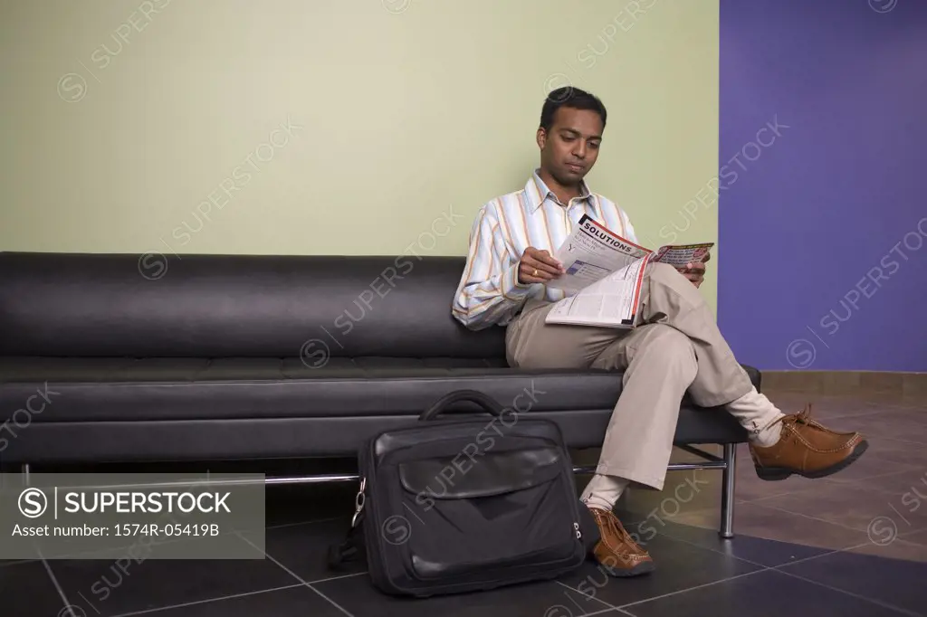 Businessman sitting on a couch reading a magazine in an office
