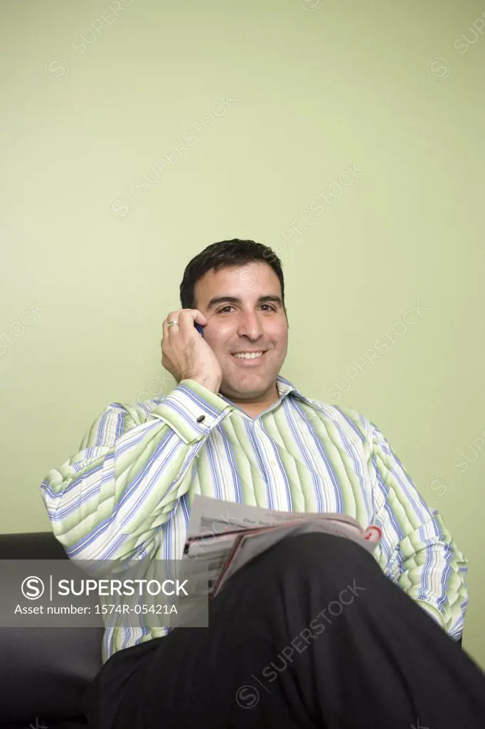 Businessman sitting on a couch talking on a mobile phone in an office