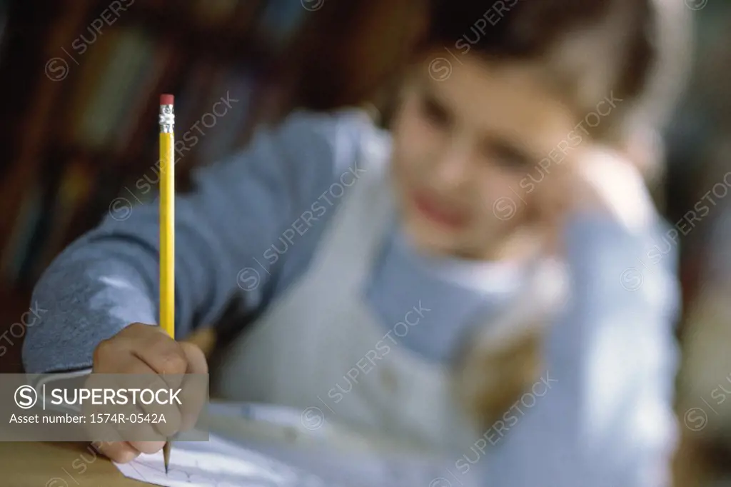 Close-up of a girl sitting and writing with a pencil