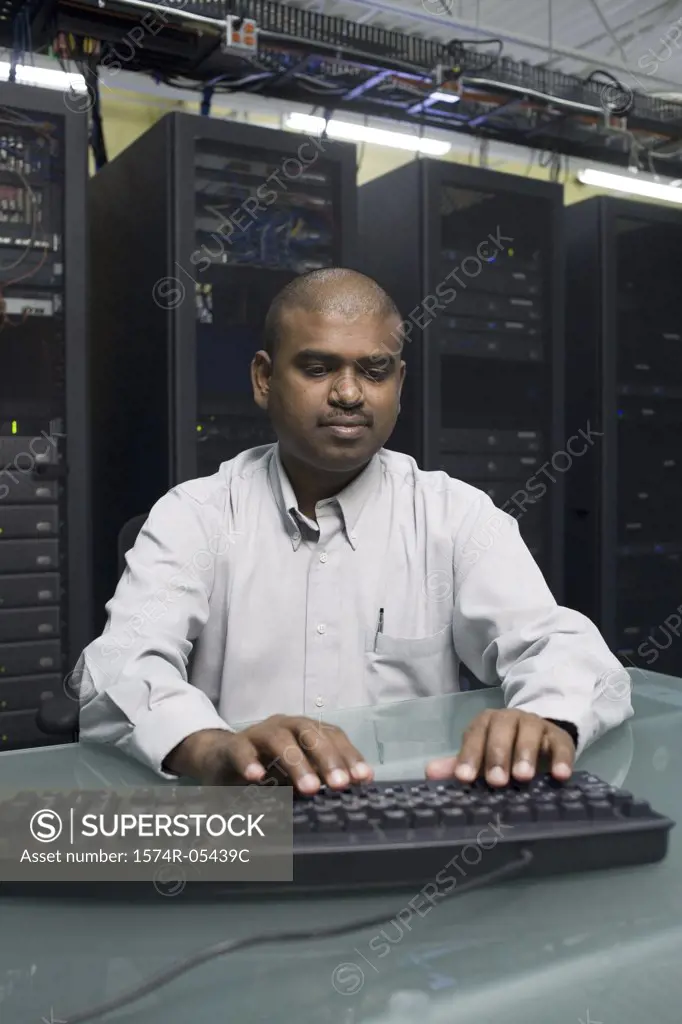 Technician working on a computer sitting in a server room