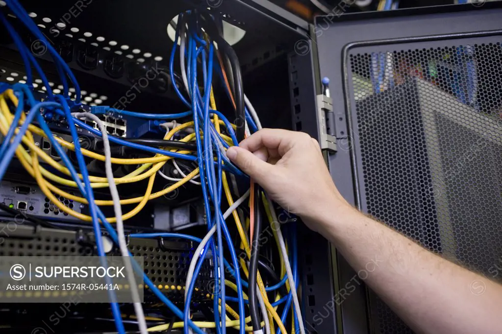 Close-up of a human hand attaching cables to a network server