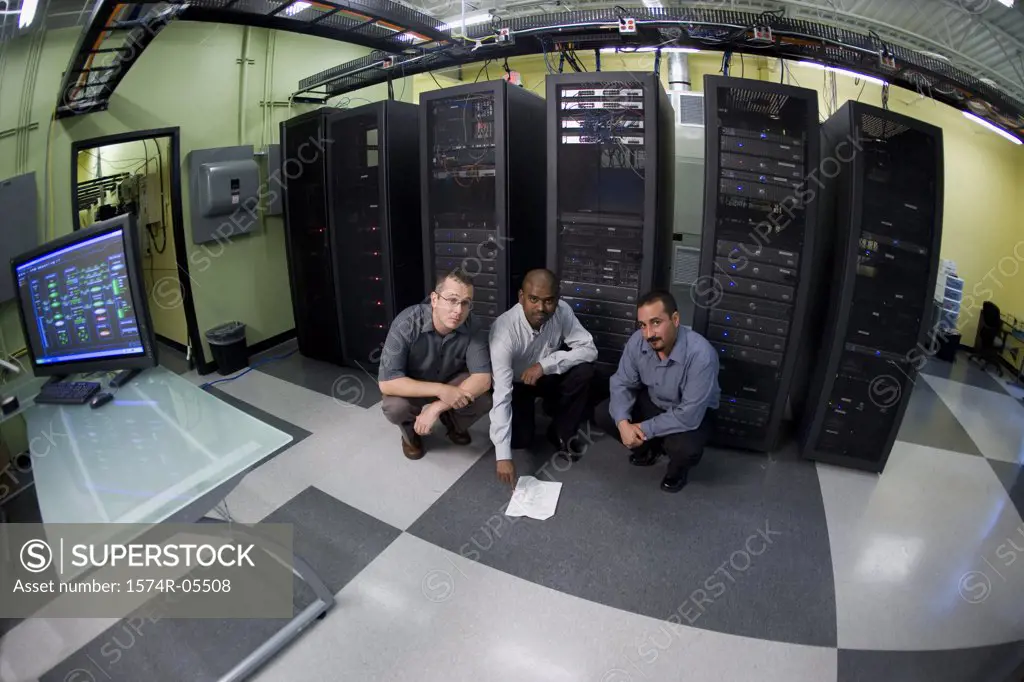 Portrait of three technicians crouching in front of a network server