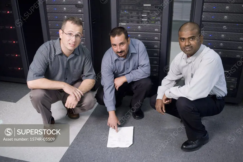 Portrait of three technicians crouching in front of a network server