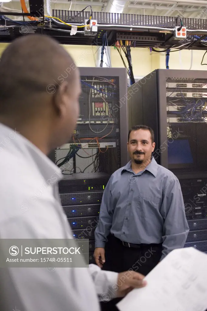 Two technicians talking in front of a network server