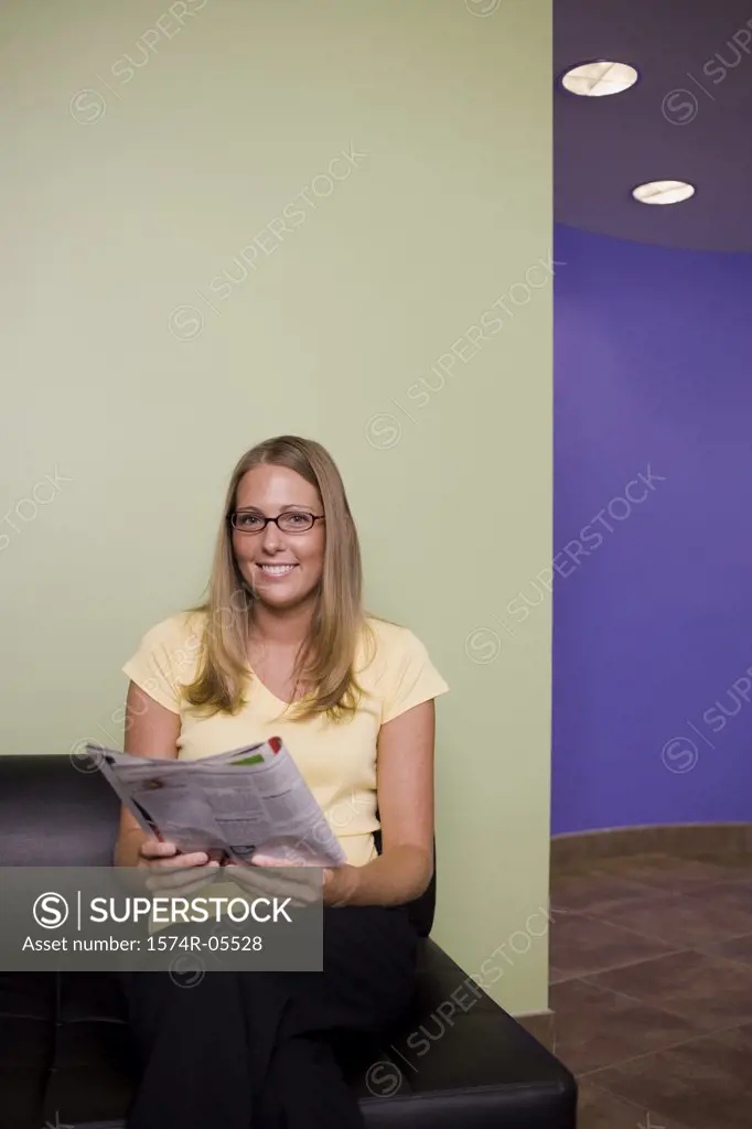 Portrait of a businesswoman sitting on a couch holding a magazine
