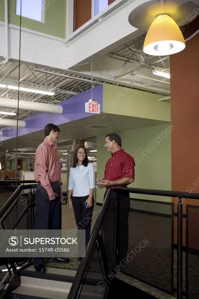 Two businessmen and a businesswoman standing on stairs
