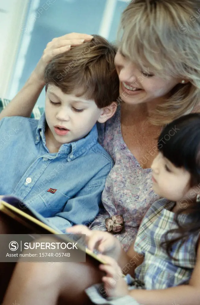 Mother reading a book with her son and daughter