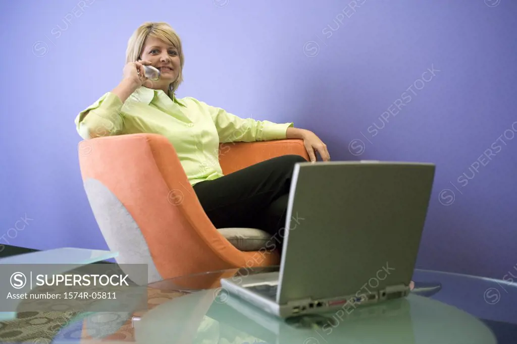 Portrait of a businesswoman sitting in front of a laptop talking on a mobile phone