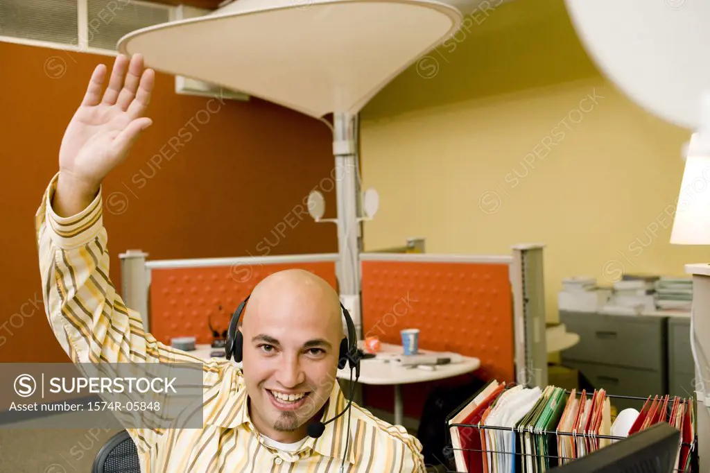 Portrait of a male customer service representative wearing a headset with his hand raised