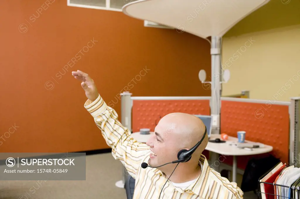 Male customer service representative wearing a headset with his hand raised