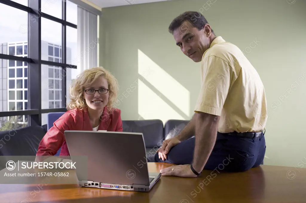 Portrait of a businessman and a businesswoman sitting in front of a laptop
