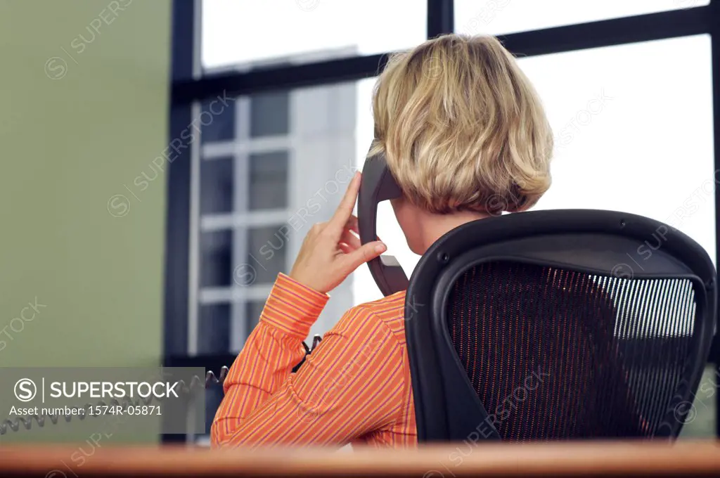 Rear view of a businesswoman sitting in an office talking on a telephone