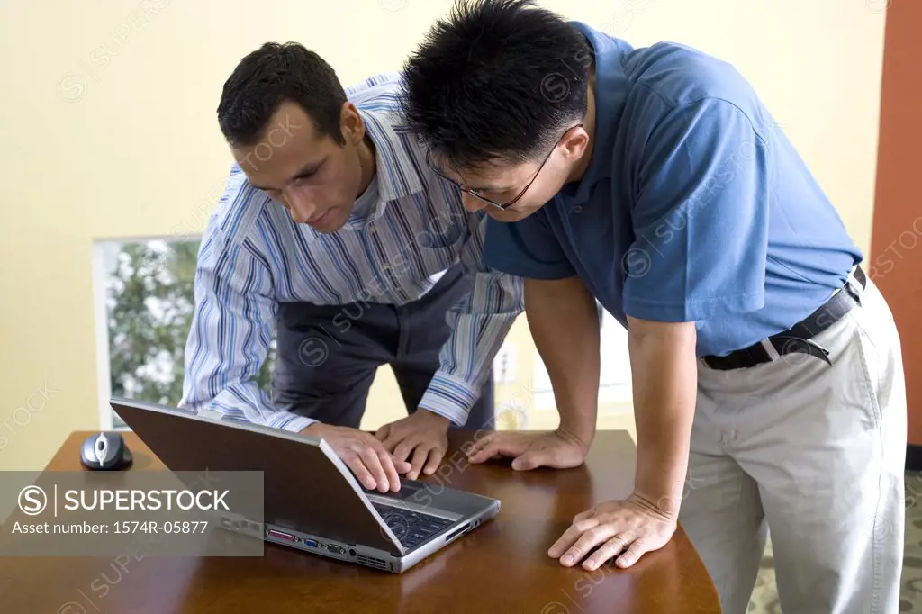 Two businessmen standing looking at a laptop