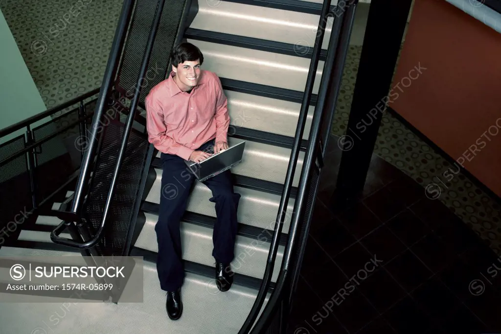 Portrait of a businessman sitting on stairs working on a laptop