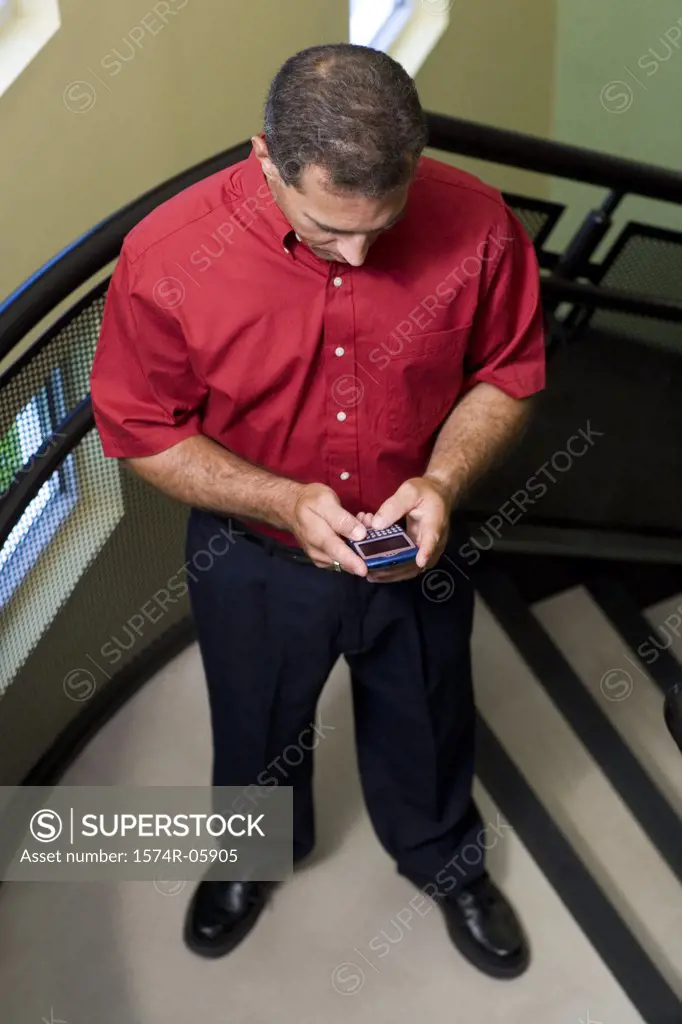 High angle view of a businessman standing on stairs holding a mobile phone