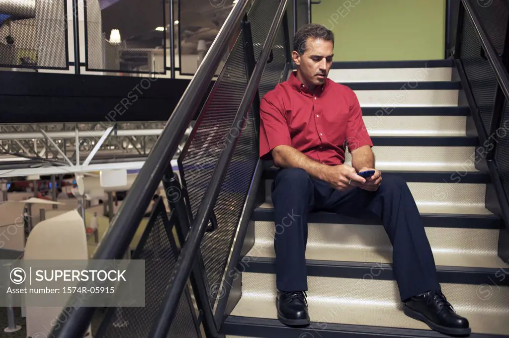 Businessman sitting on stairs holding a mobile phone