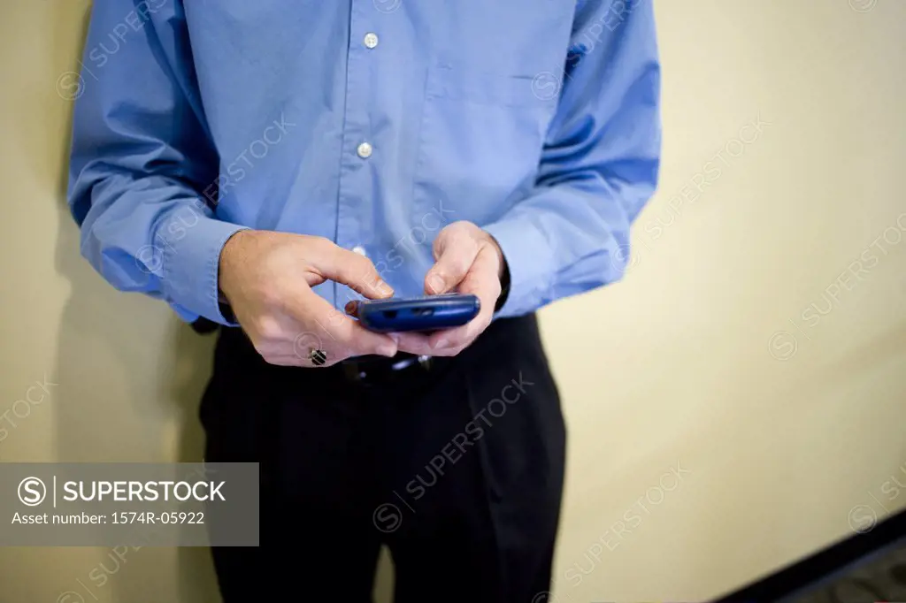 Mid section view of a businessman standing in an office holding a palmtop