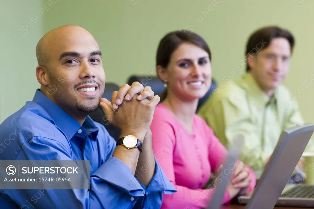 Two businessmen and a businesswoman sitting in a conference room smiling