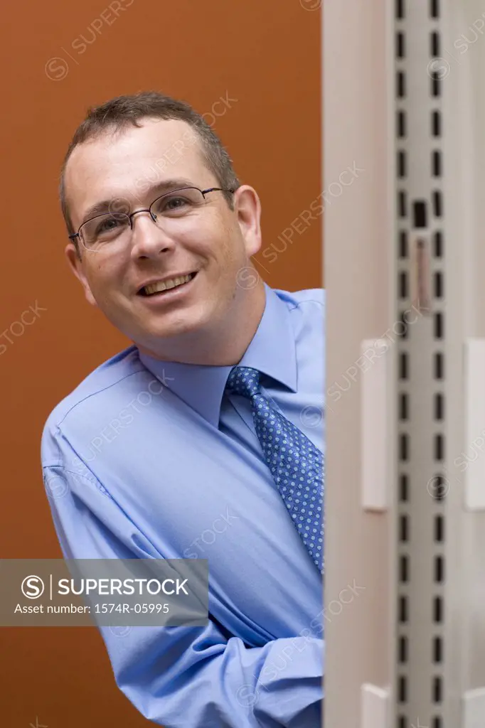 Portrait of a businessman peeking from behind a wall