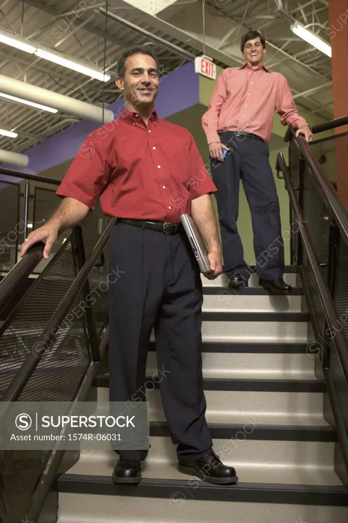 Portrait of two businessmen standing on stairs in an office