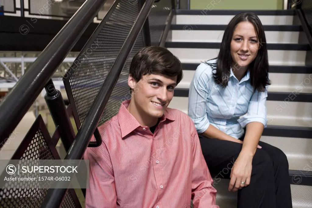 Portrait of a businessman and a businesswoman sitting on stairs