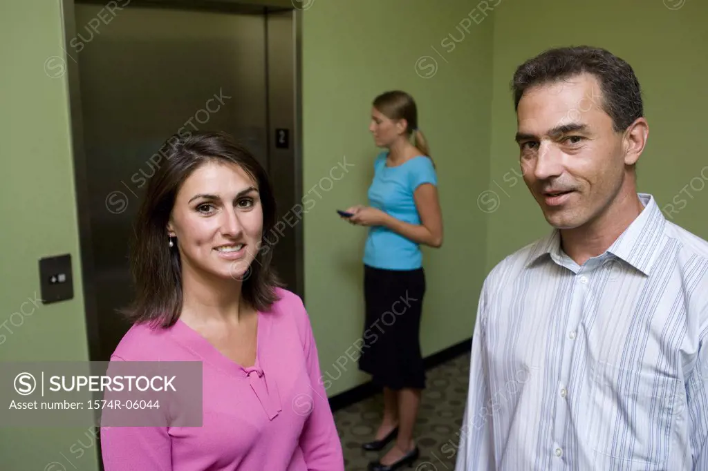 Portrait of a businesswoman and a businessman standing in front of an elevator