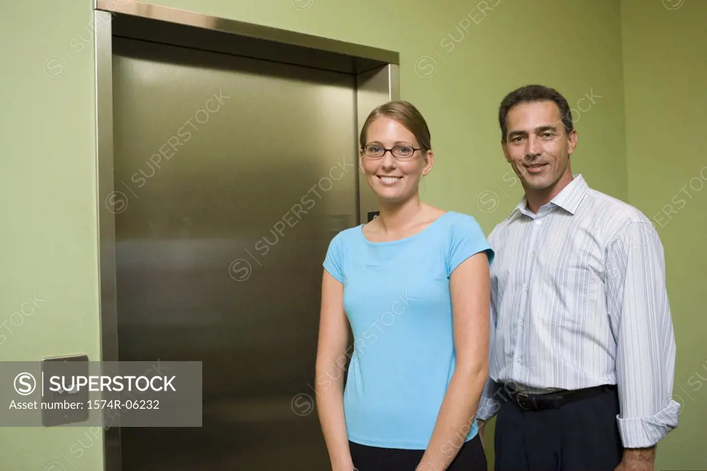 Portrait of a businessman and a businesswoman standing near an elevator