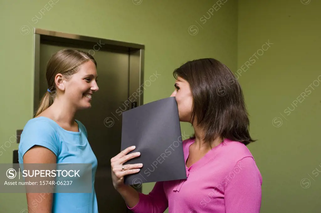 Side profile of two businesswomen standing near an elevator