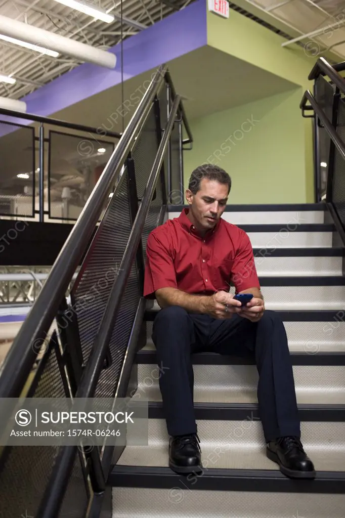 Businessman holding a mobile phone sitting on a staircase