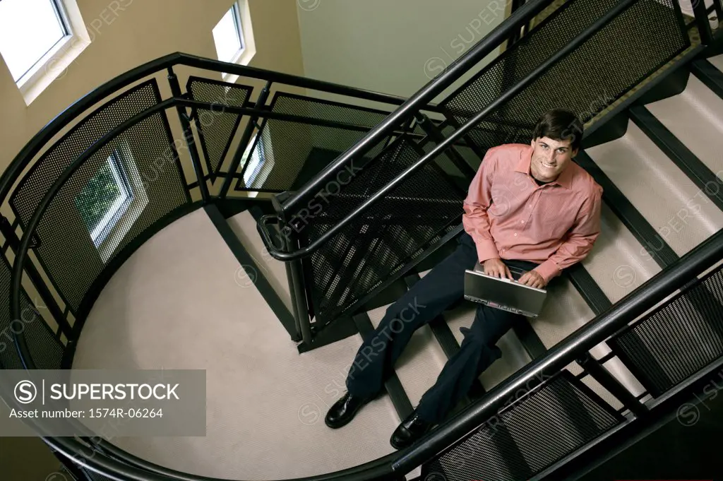Portrait of a businessman sitting on a staircase working on a laptop