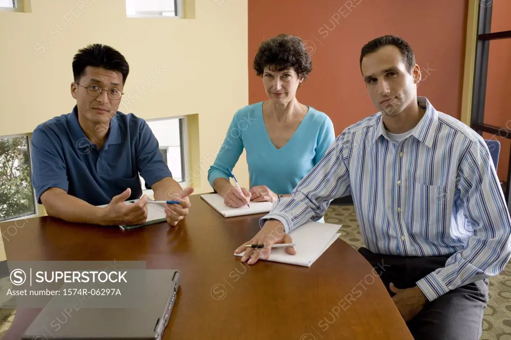 Portrait of two businessmen and a businesswoman sitting in an office