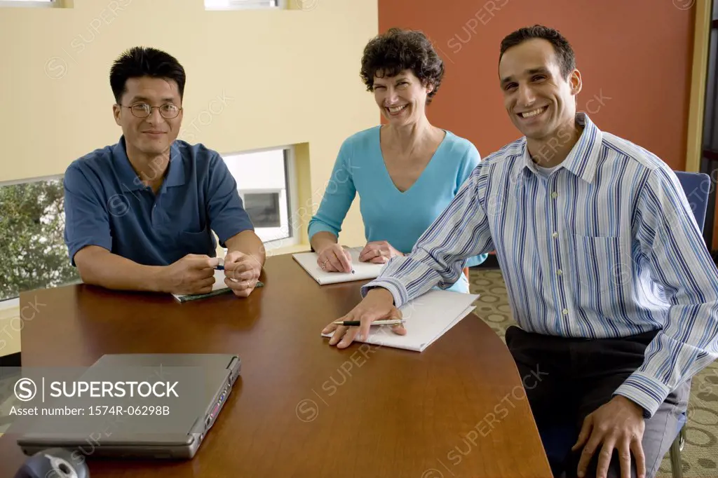 Portrait of two businessmen and a businesswoman sitting in an office