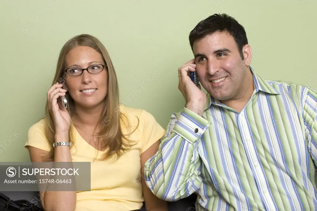 Close-up of a businessman and a businesswoman talking on mobile phones