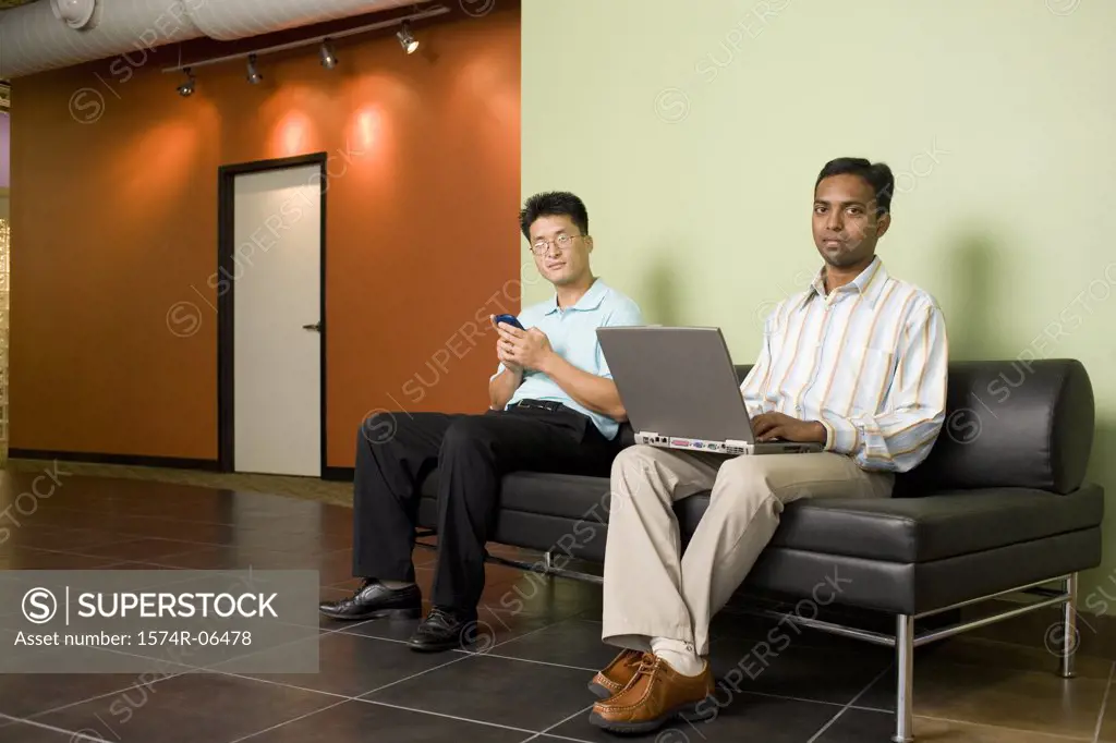 Portrait of two businessmen sitting on a couch in an office