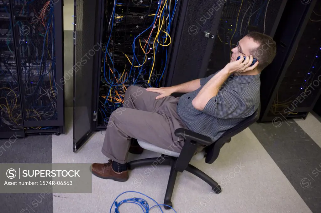 High angle view of a technician talking on a mobile phone in a server room
