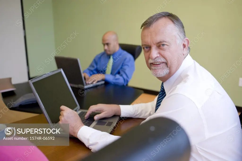 Two businessmen working on laptops in an office