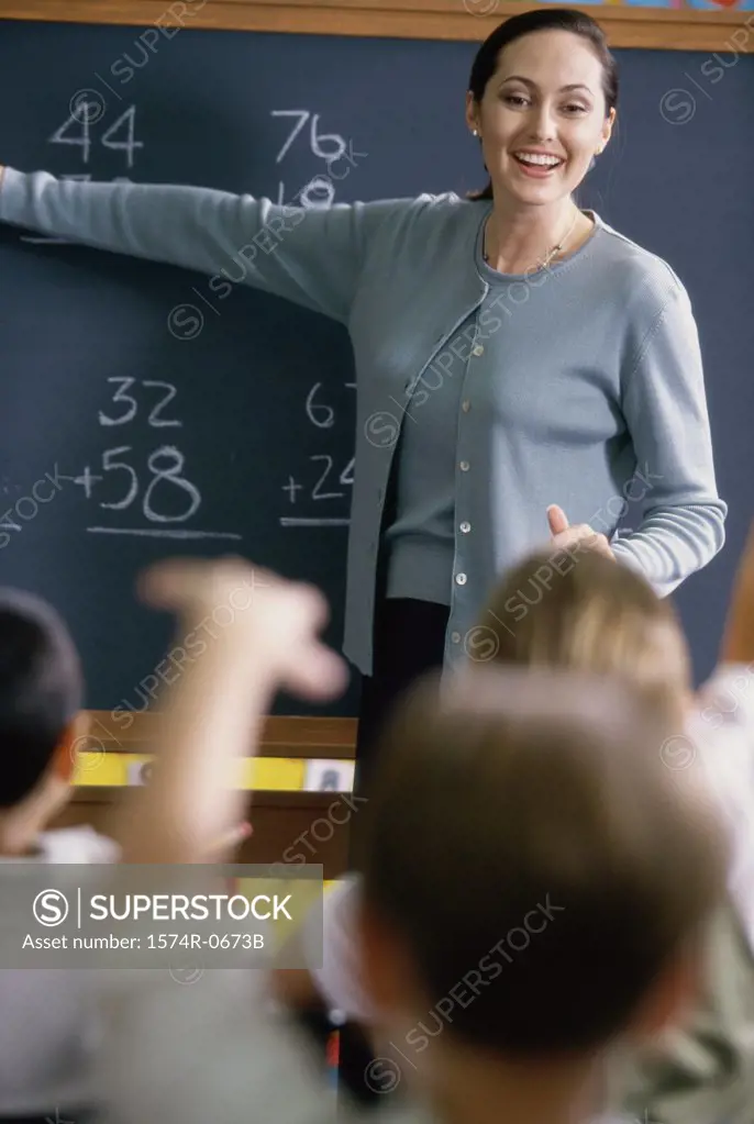 Female teacher pointing to a chalkboard in a classroom