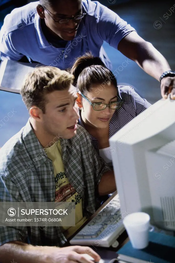 High angle view of two young men and a young woman using a computer