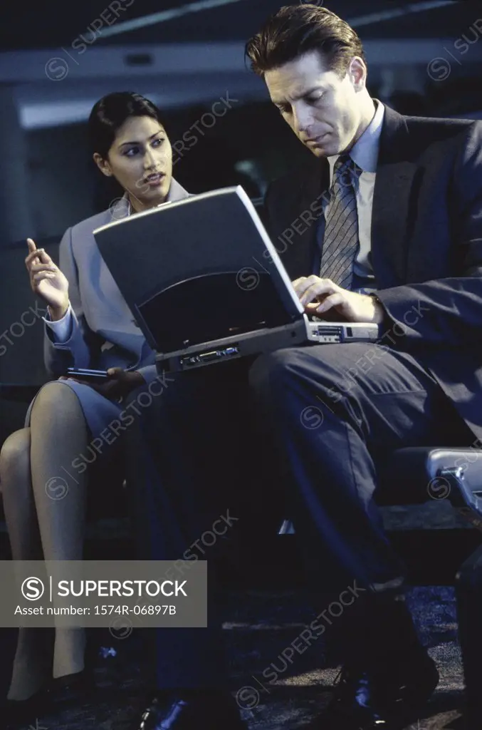 Side profile of a businessman and businesswoman sitting in front of a laptop