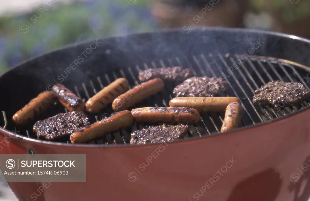 Close-up of hamburgers and hot dogs cooking on a barbecue grill